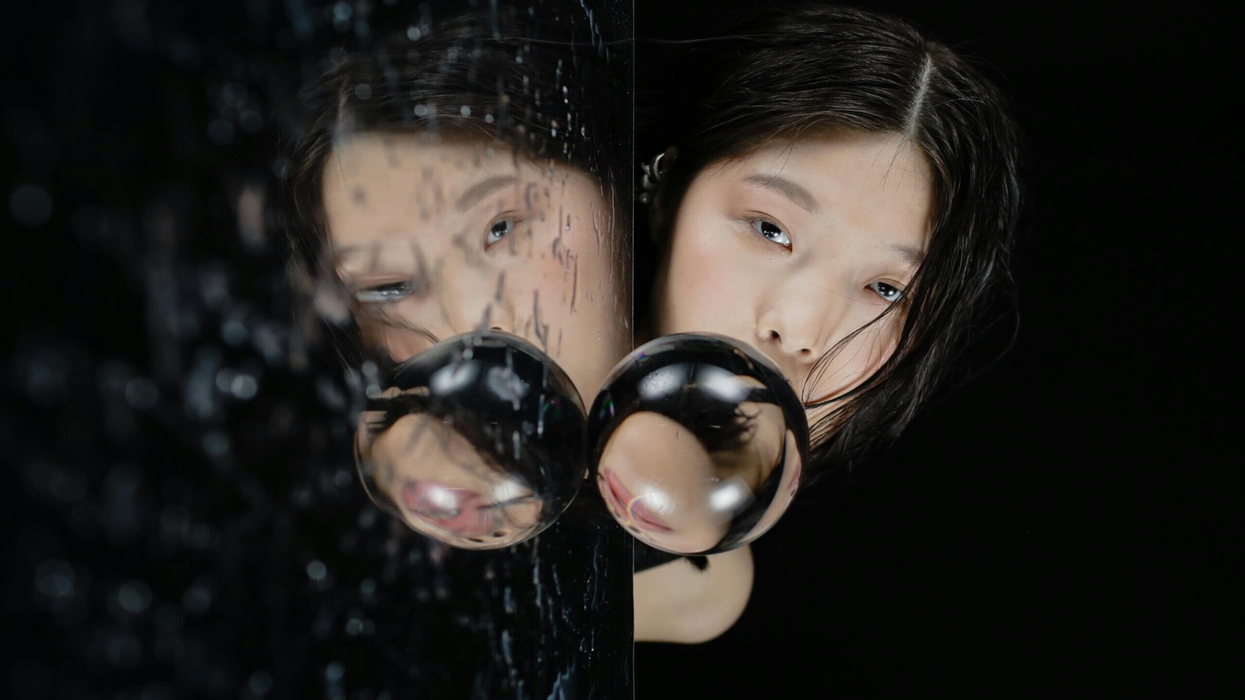 Woman gazing into a rain-splattered mirror with a distorted reflection, symbolizing deception, hidden truths, and emotional introspection.